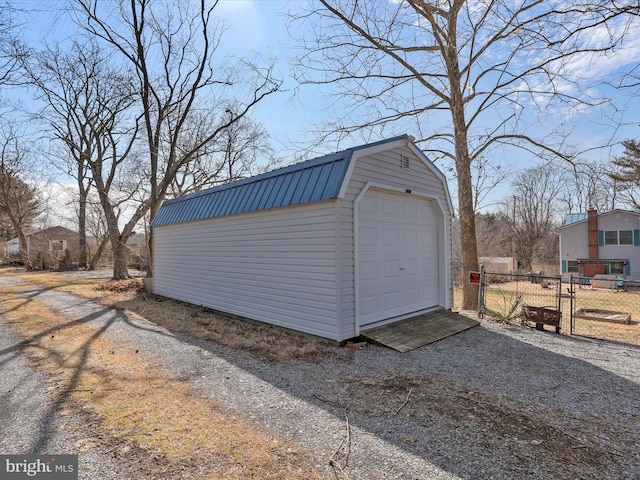 detached garage featuring gravel driveway and fence