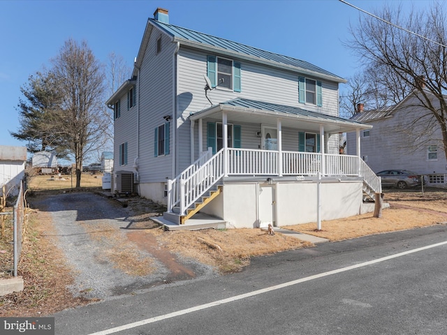 view of front of property with driveway, central AC unit, metal roof, a standing seam roof, and a porch