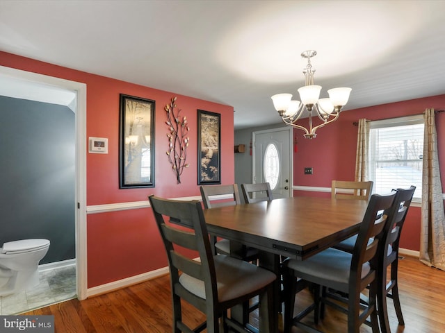 dining room featuring a notable chandelier, baseboards, and wood finished floors