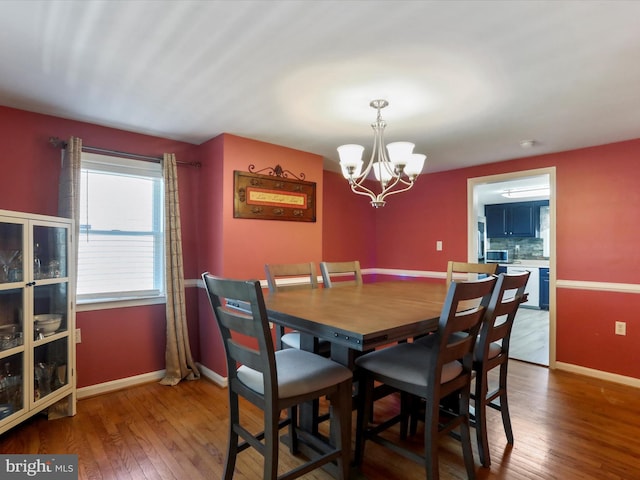 dining space featuring baseboards, a chandelier, and wood finished floors