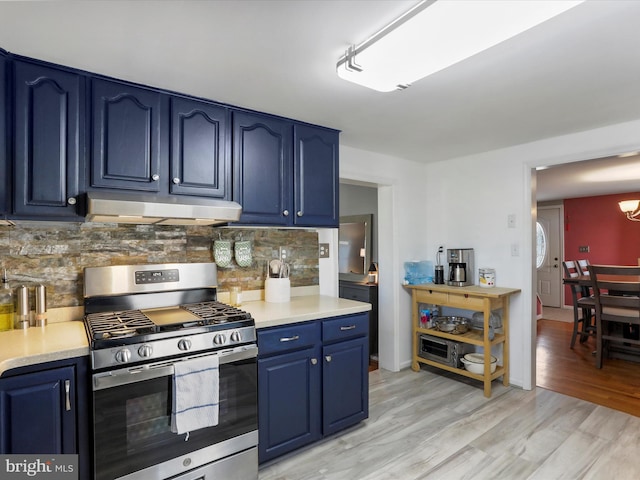 kitchen with light countertops, gas stove, blue cabinets, light wood-type flooring, and under cabinet range hood