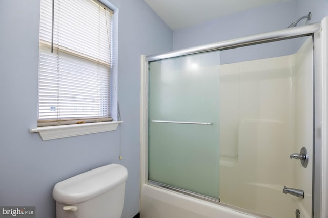 bathroom with bath / shower combo with glass door and toilet