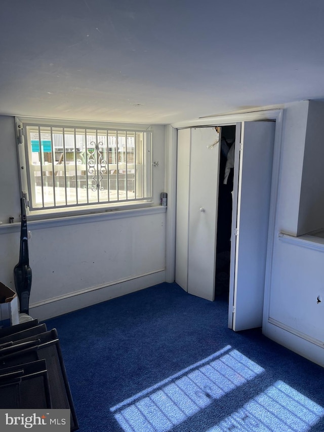 unfurnished bedroom with dark carpet and a closet