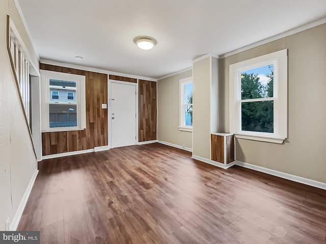 foyer entrance with ornamental molding, dark wood-type flooring, and wood walls