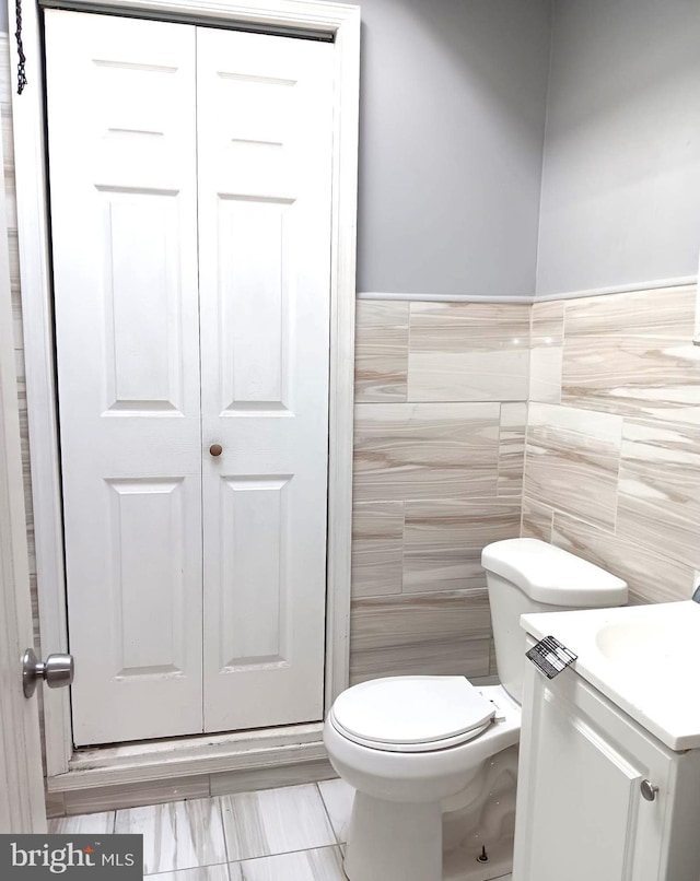 bathroom featuring vanity, tile walls, and toilet