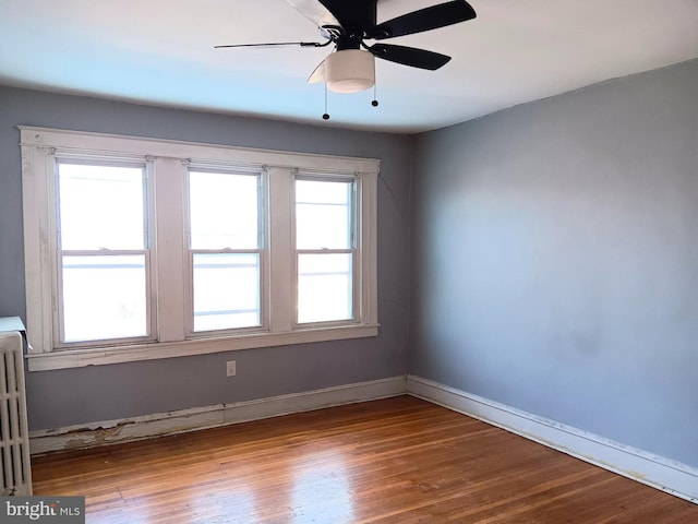 empty room with radiator, wood-type flooring, and ceiling fan