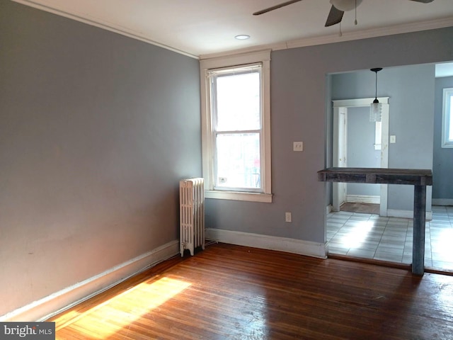 empty room featuring ornamental molding, dark hardwood / wood-style floors, radiator heating unit, and ceiling fan