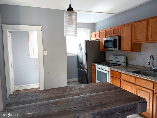 kitchen with stainless steel appliances, tasteful backsplash, hanging light fixtures, and sink