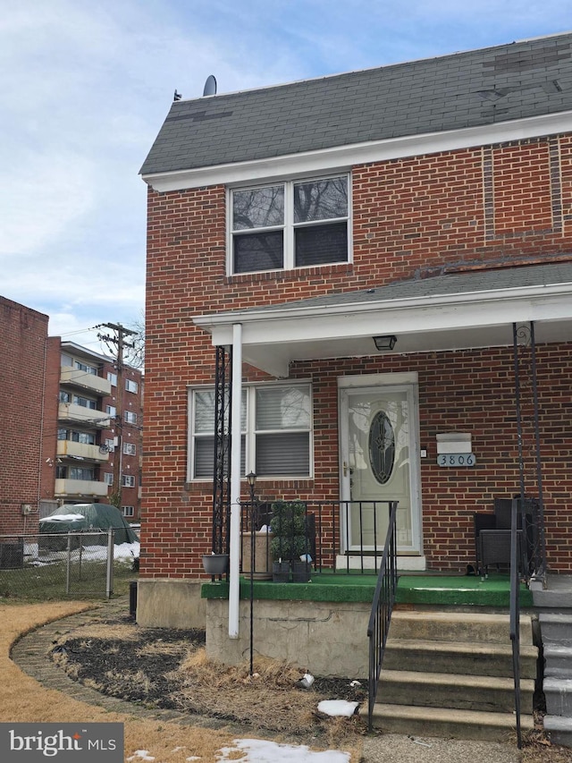 view of front of home featuring brick siding and roof with shingles