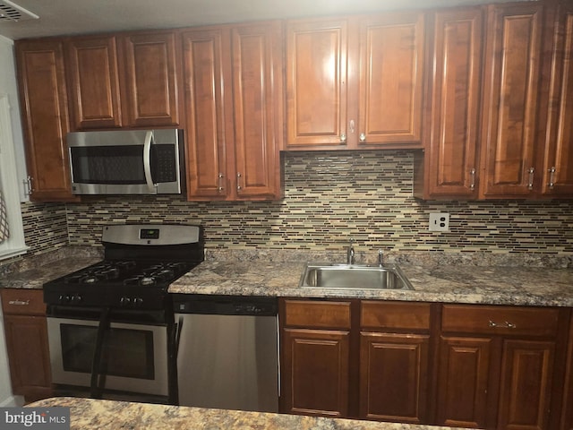 kitchen with stone counters, stainless steel appliances, visible vents, decorative backsplash, and a sink