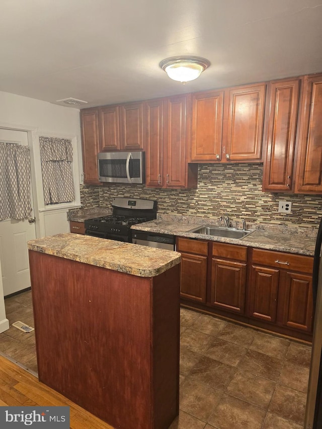 kitchen featuring stainless steel appliances, tasteful backsplash, a sink, and light stone counters