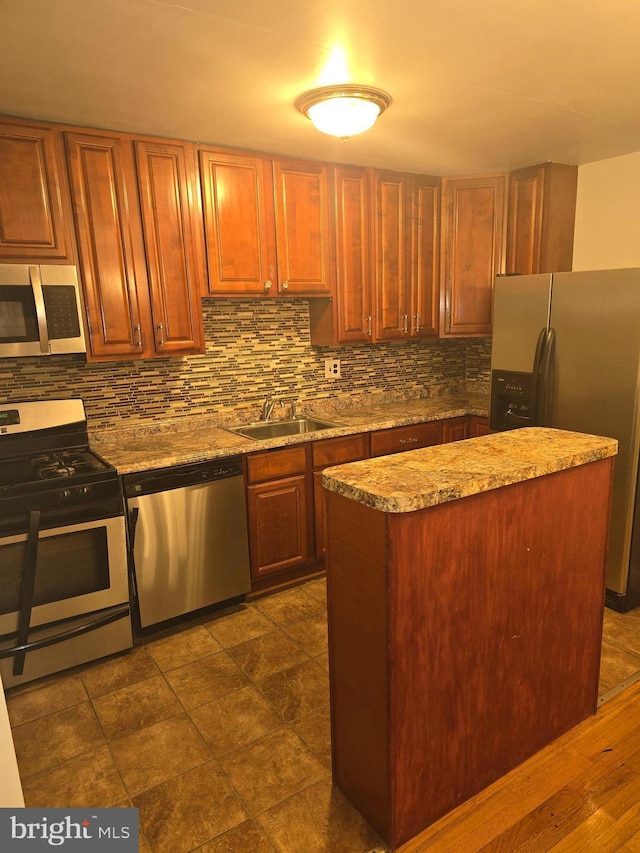 kitchen featuring light stone counters, a sink, a center island, appliances with stainless steel finishes, and decorative backsplash