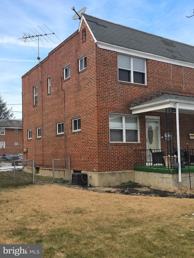 exterior space featuring a yard, fence, central AC, and brick siding