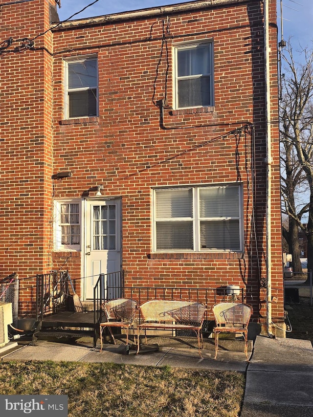 view of front facade with brick siding and a patio