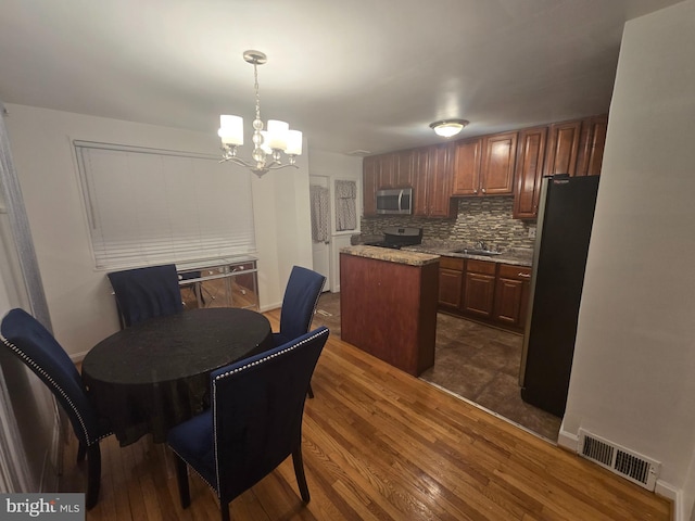 dining space featuring dark wood-style floors, baseboards, visible vents, and a chandelier