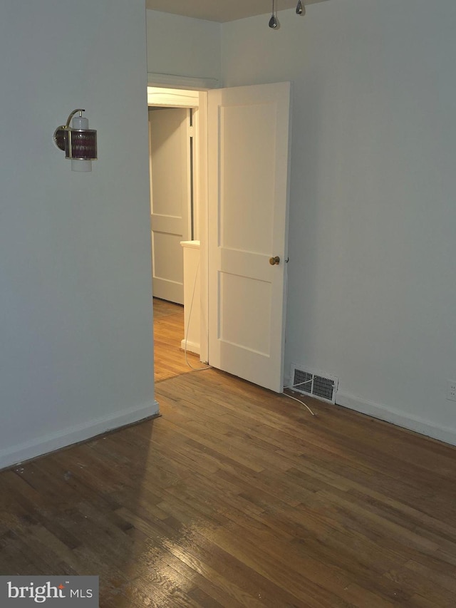 empty room featuring baseboards, visible vents, and dark wood-type flooring