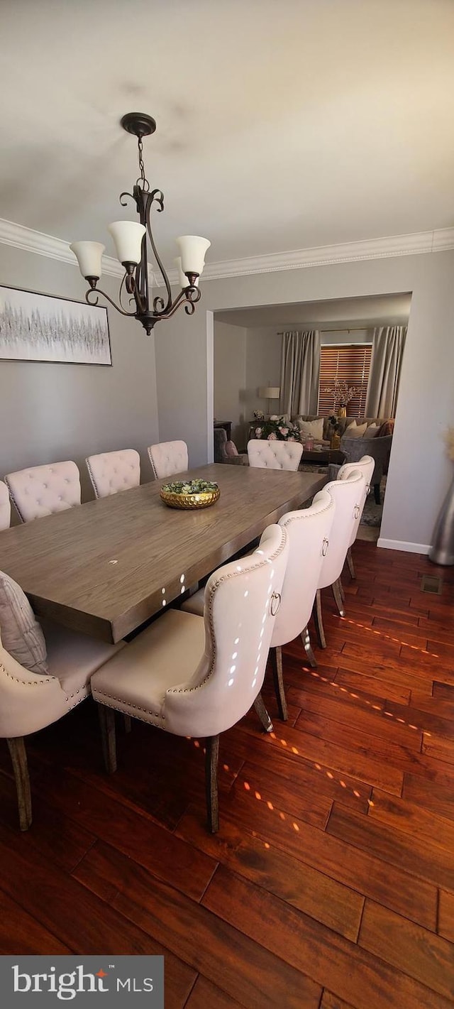 dining room featuring dark wood-style flooring, crown molding, baseboards, and an inviting chandelier