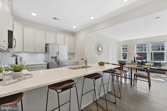 kitchen featuring a kitchen bar, appliances with stainless steel finishes, white cabinets, and a sink