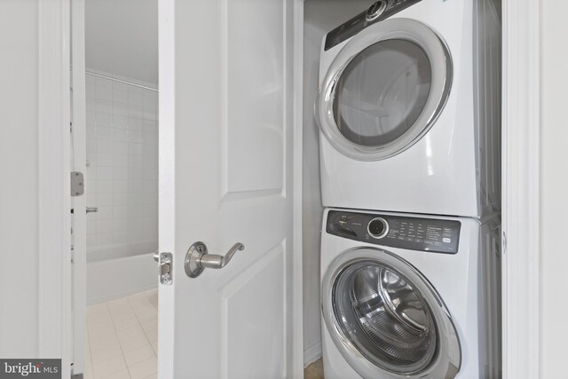 clothes washing area with laundry area, light tile patterned floors, and stacked washer / dryer