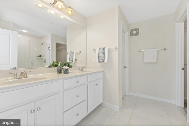 bathroom with double vanity, a stall shower, baseboards, and a sink