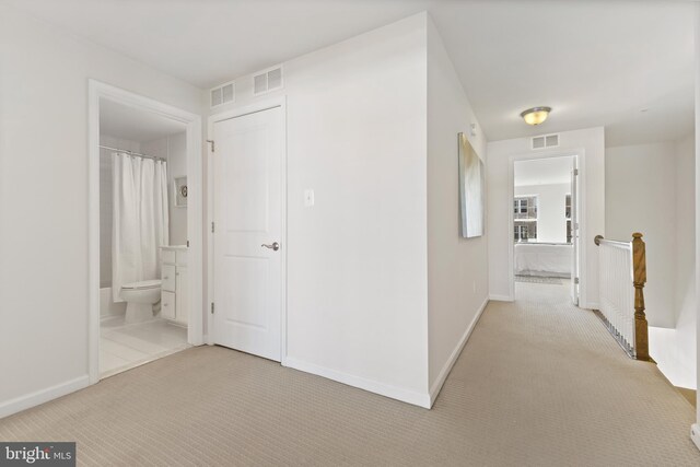 corridor with visible vents, light carpet, and baseboards