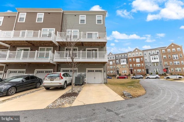 view of property featuring driveway, an attached garage, and central AC unit