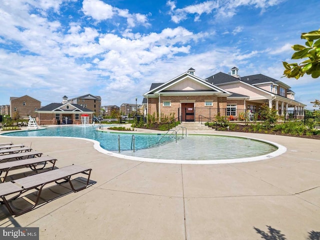 community pool featuring a residential view, fence, and a patio