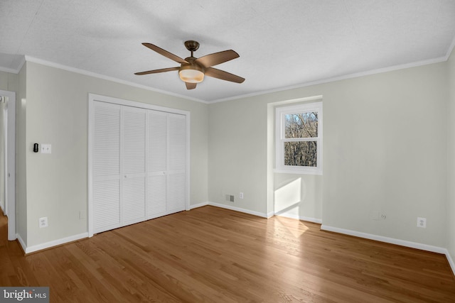 unfurnished bedroom featuring hardwood / wood-style floors, ornamental molding, a closet, and ceiling fan