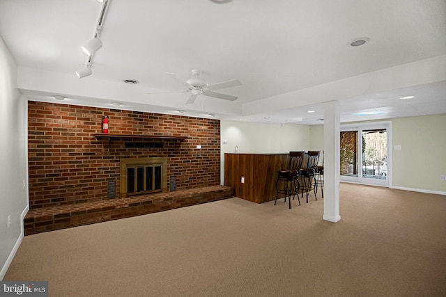 unfurnished living room with rail lighting, bar area, a brick fireplace, carpet flooring, and ceiling fan