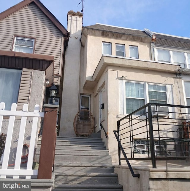 view of front of house with a chimney and stucco siding