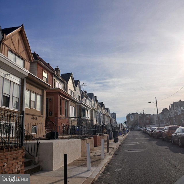 view of road with street lighting, a residential view, curbs, and sidewalks