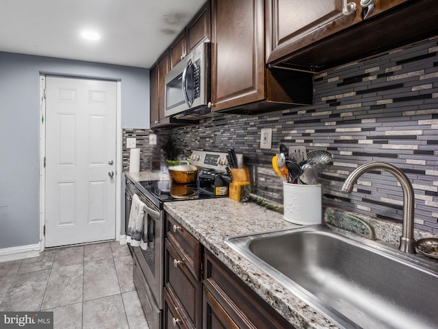 kitchen with a sink, tasteful backsplash, appliances with stainless steel finishes, and dark brown cabinetry