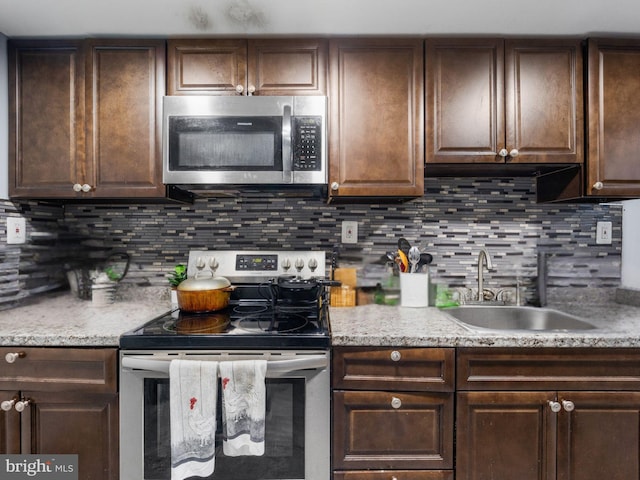 kitchen featuring a sink, stainless steel appliances, backsplash, and dark brown cabinetry