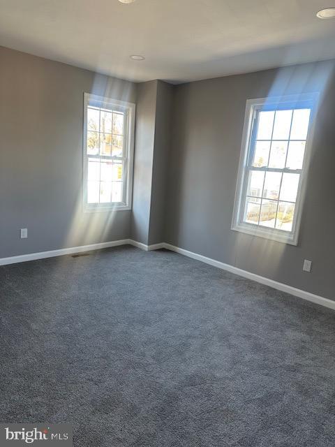 spare room with dark colored carpet