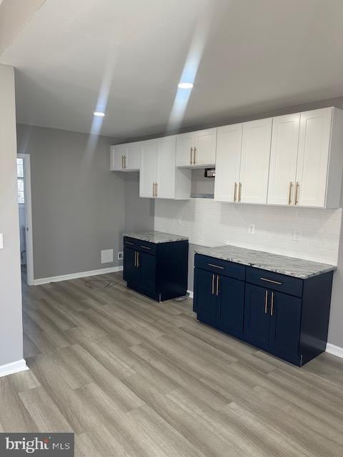 kitchen featuring blue cabinets, white cabinets, and decorative backsplash