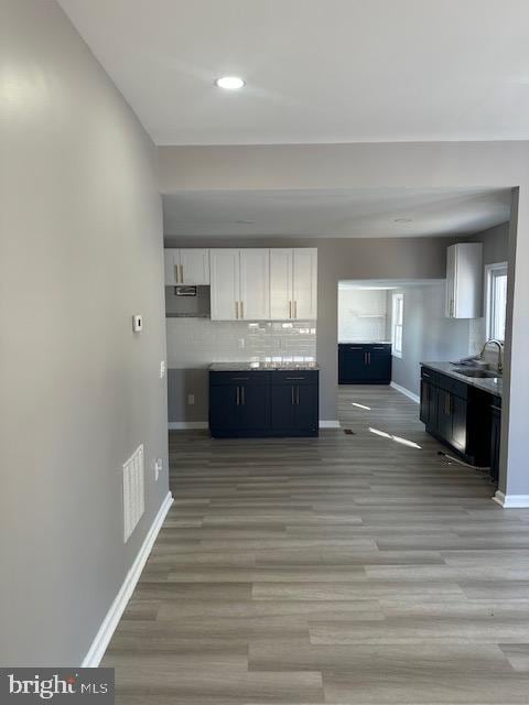 kitchen featuring white cabinetry, sink, decorative backsplash, and light hardwood / wood-style flooring