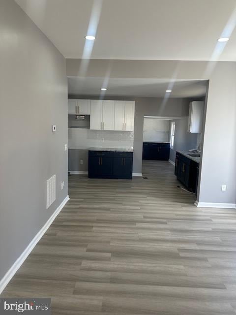 kitchen with tasteful backsplash, white cabinetry, ventilation hood, and light hardwood / wood-style flooring