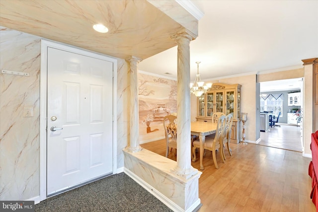 dining area with a notable chandelier, hardwood / wood-style flooring, ornamental molding, and ornate columns