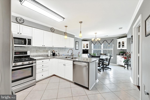 kitchen with appliances with stainless steel finishes, white cabinetry, sink, light tile patterned floors, and light stone counters