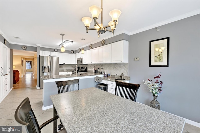 kitchen with white cabinetry, hanging light fixtures, appliances with stainless steel finishes, and a center island with sink