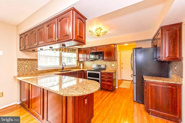 kitchen featuring stainless steel appliances, a sink, a peninsula, and dark brown cabinets