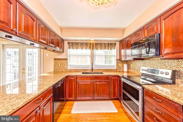 kitchen with dishwasher, light stone countertops, double oven range, black microwave, and a sink