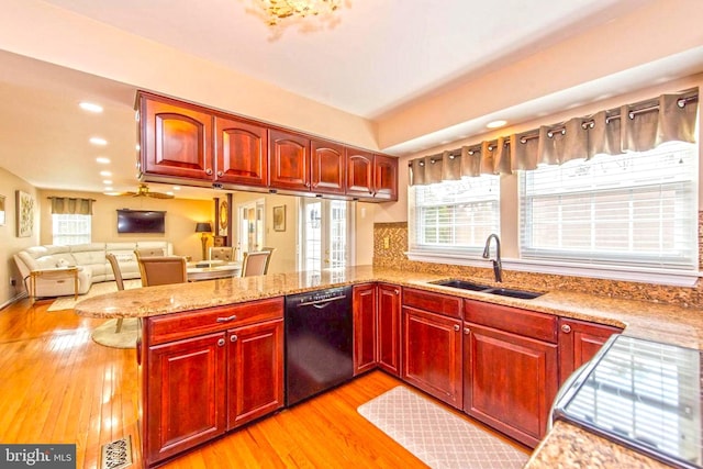 kitchen with a sink, dark brown cabinets, light stone countertops, dishwasher, and a peninsula