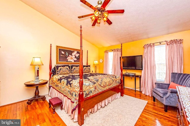 bedroom with lofted ceiling, ceiling fan, a textured ceiling, and wood-type flooring