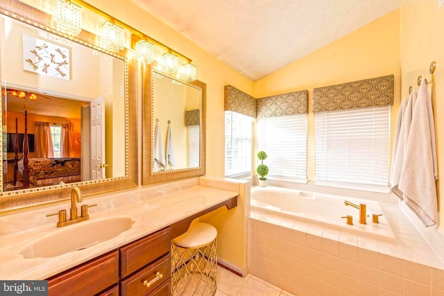 ensuite bathroom with lofted ceiling, tile patterned flooring, vanity, a bath, and ensuite bath