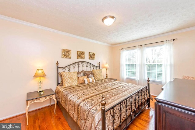 bedroom featuring a textured ceiling, ornamental molding, light wood-type flooring, and baseboards