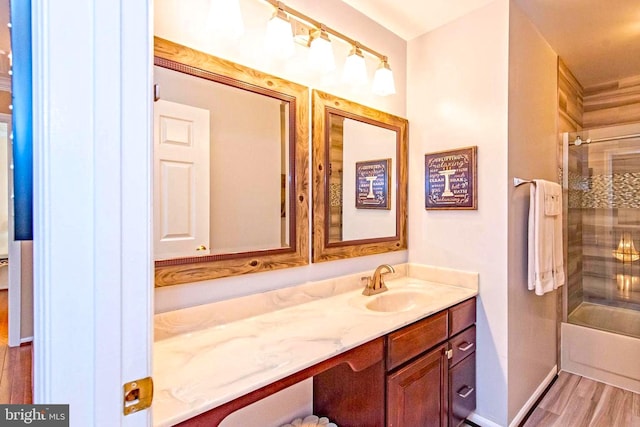 full bath with enclosed tub / shower combo, baseboards, wood finished floors, and vanity