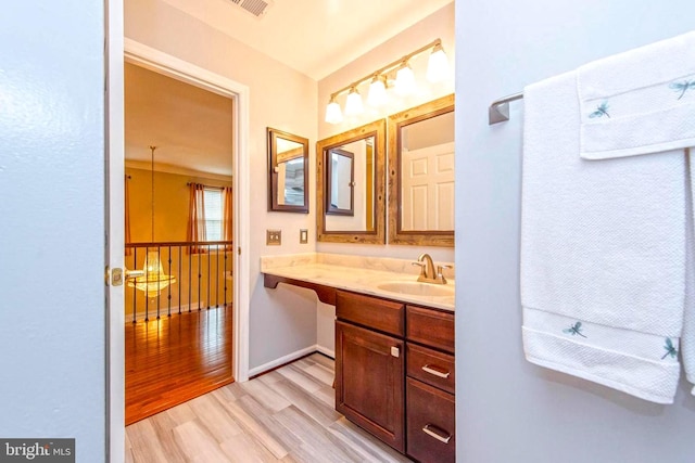 bathroom featuring visible vents, vanity, baseboards, and wood finished floors