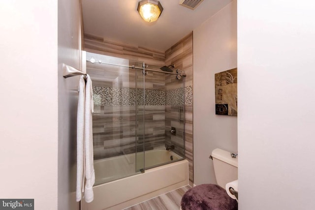 bathroom with visible vents, shower / bath combination with glass door, toilet, and wood finished floors