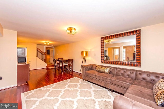 living area featuring stairway, hardwood / wood-style flooring, and baseboards